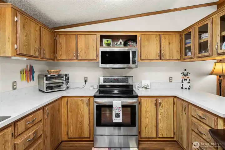 Kitchen features a stainless steel electric range with microwave, complemented by generous cabinetry and an efficient layout for everyday cooking.