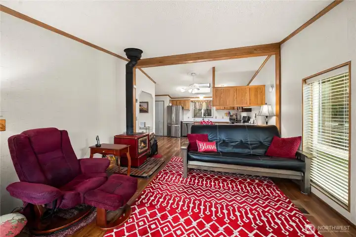 Comfortable den adjacent to the kitchen features a wood-burning stove, creating a cozy retreat for relaxing or quiet evenings at home.