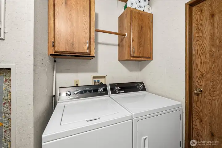 Dedicated laundry area features washer and dryer with overhead cabinetry for organized storage.