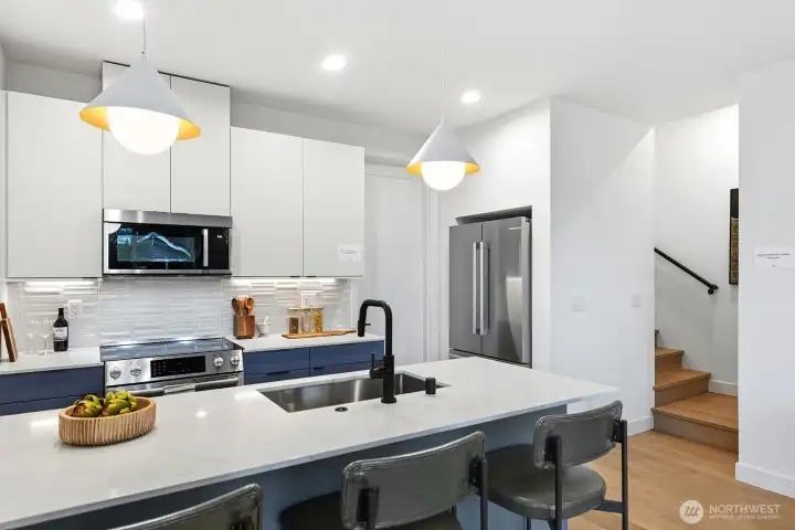 Quartz counters, under-cabinet lighting, SS appliances, and stylish backsplash.