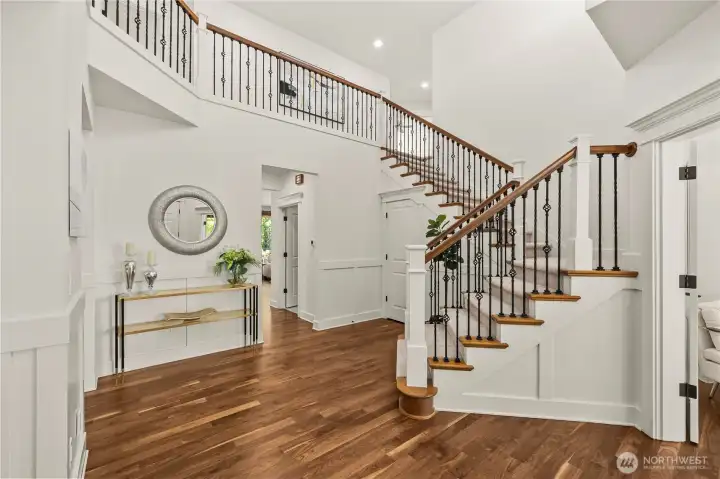 Grand entry with soaring ceilings, rich hardwood flooring, and elegant Craftsman-inspired millwork