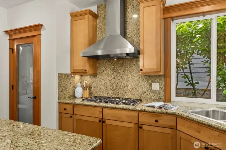 Well-equipped chef’s kitchen featuring a premium gas cooktop with a vent hood