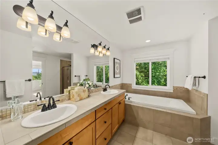 Spa-inspired primary bathroom featuring dual vanities and a soaking tub