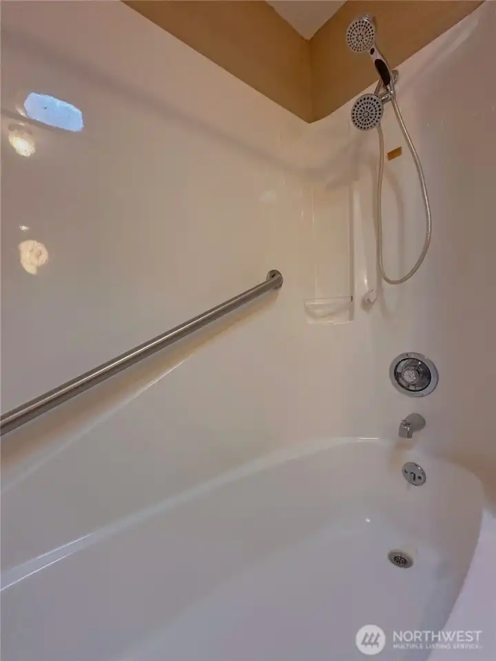 Tub and shower combination with built-in grab bars for added comfort and accessibility.