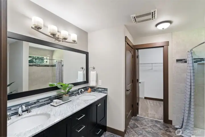 Another view of the primary bath with double sinks, shower, and walk-in closet.