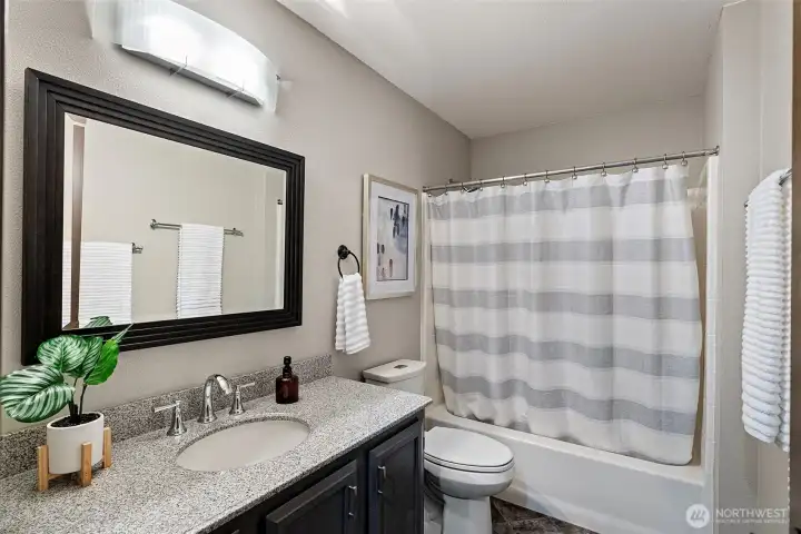 The guest bath includes a tub/shower combination, refreshed vanity, lighting, and flooring.