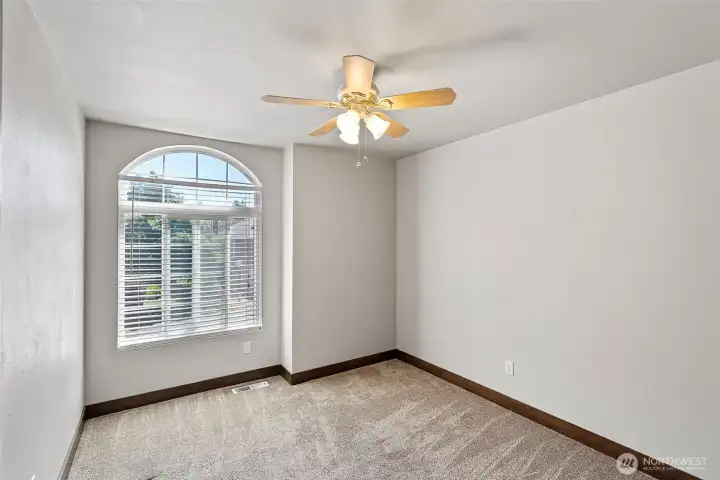 The third bedroom with ceiling fan and arched window that adds character and light.
