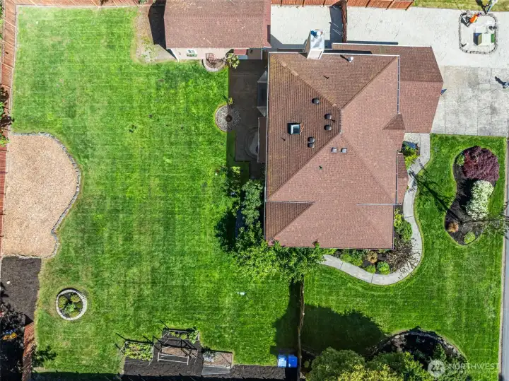Drone view of this amazing home and property with extra shop/garage, garden beds, lovely landscaping and level yard.