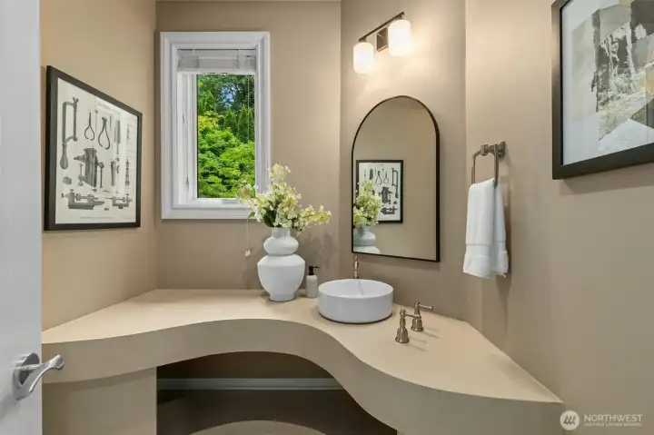 The main floor powder room features a custom curved countertop & stylish vessel sink. The main floor powder room features a custom curved countertop & stylish vessel sink.