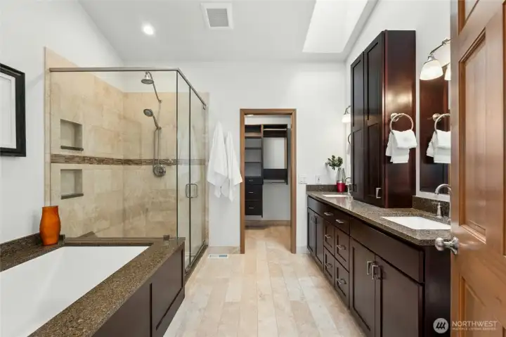 Remodeled primary bath with soaking tub, walk in shower, heated tile floors and double vanity with sinks.