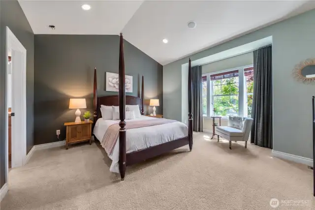 Retreat to this elegant primary bedroom featuring a dramatic vaulted ceiling, rich accent wall, and an abundance of natural light.