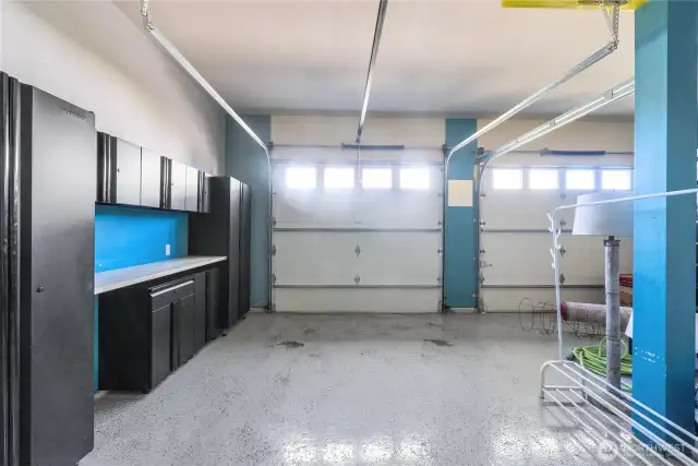 Spacious garage includes epoxy flooring and husky shelving with built-in workspace.