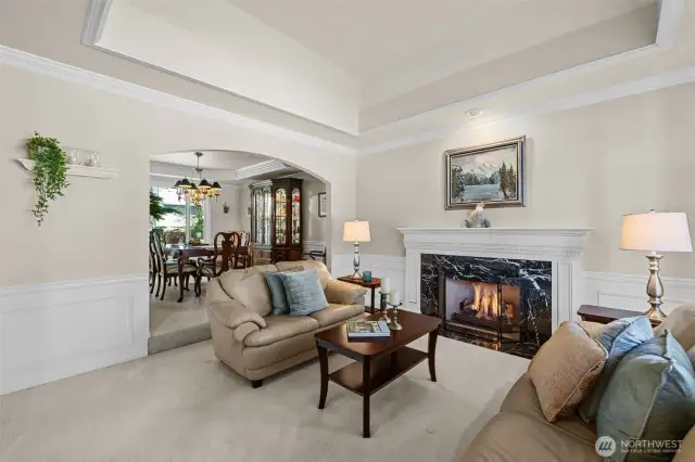 Coffered ceiling over formal living room, extensive mill work package, and natural gas fireplace with intricate wood wrapped mantel.