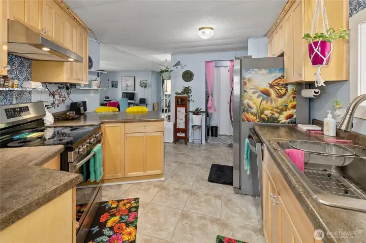 View of the kitchen looking back at entrance and remodeled laundry area that features Washer/Dryer combo stainless steel brand NEW and energy efficent with built-ins for storage.
