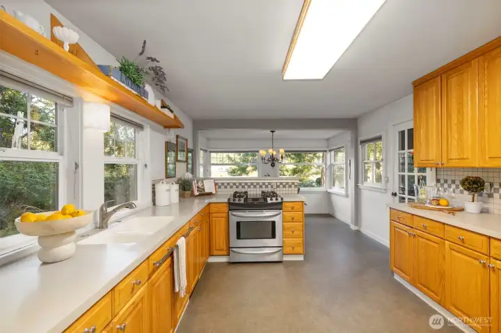 Kitchen boasts well-designed storage, wood cabinets, tile accents, and oodles of counter space.