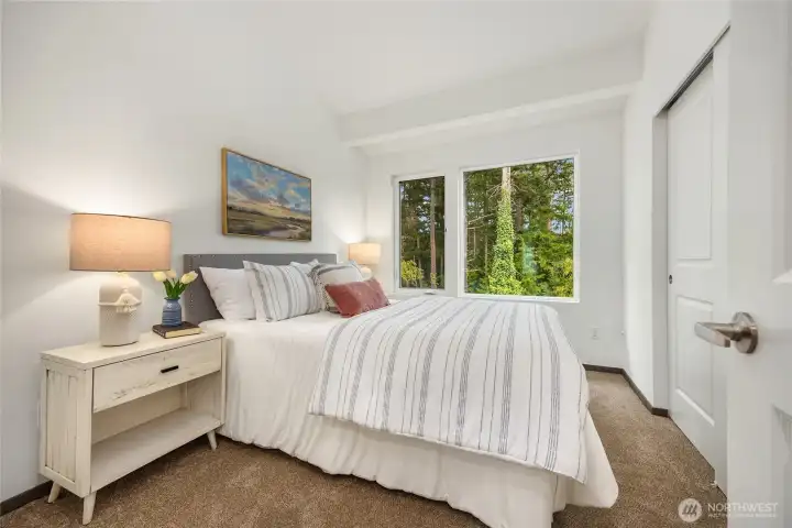 Primary bedroom with sizeable closet looks out to the forest views.