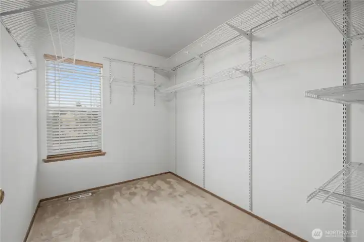 Primary walk-in closet with window and room to sit.