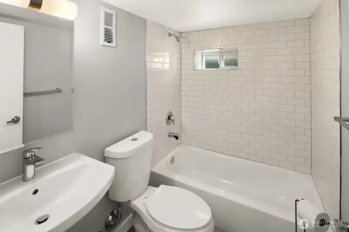 Hall bath features full tub and shower wtih tile surround.