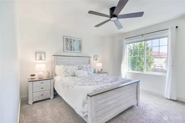 Large primary bedroom with blackout shades, ceiling fan w/ light