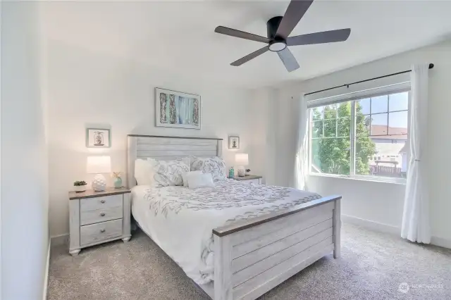 Large primary bedroom with custom room darkening shades, ceiling fan w/ light