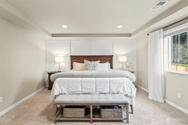 The spacious primary suite full of natural light, coffered ceilings, and wainscoting