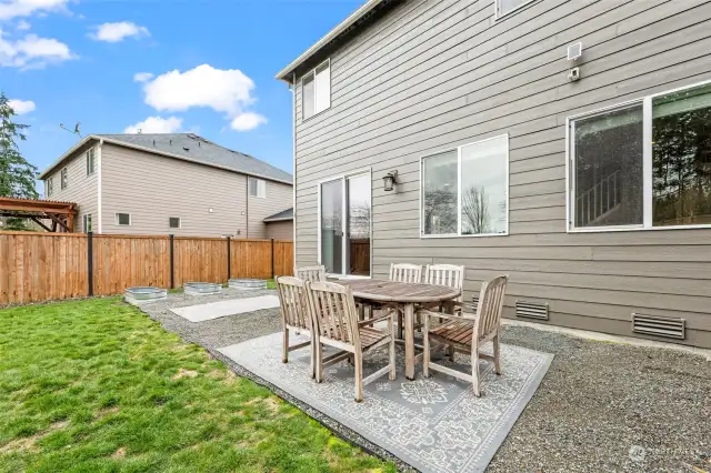 From the back steps to the end of the house near the raised garden beds has a cement slab that is currently covered with gravel