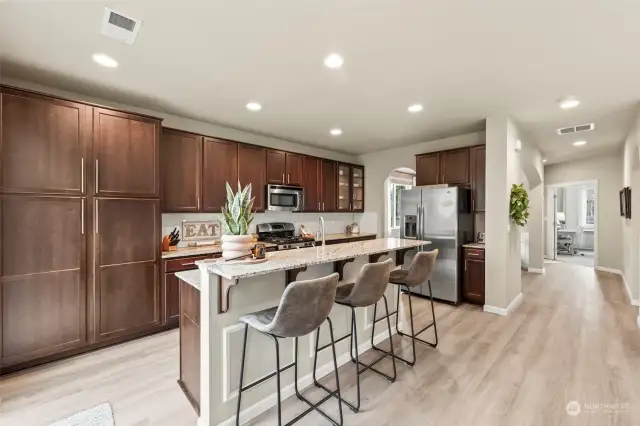 The stunning kitchen has rich wood cabinets, an island with barstool seating, and stainless steel appliances