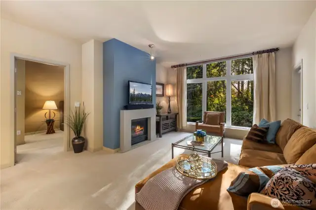 Open living area featuring floor-to-ceiling windows that flood the space with natural light and offer serene views of Wildwood Park.
