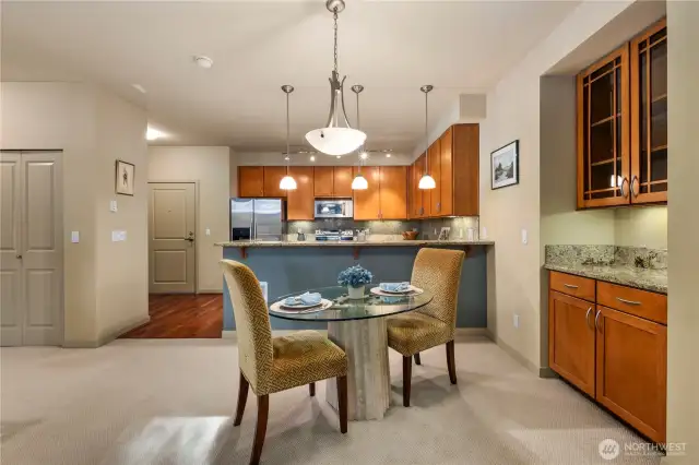 The kitchen offers both convenient eating space and a stylish bar area, perfect for casual meals or entertaining. It features additional cabinetry for ample storage, along with under-cabinet lighting that enhances the space with a warm, inviting glow.