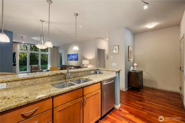 While present at the kitchen sink, you'll enjoy a clear view into the open living and dining areas, creating a connected and spacious feel. Beyond, large windows and the back door offer a glimpse of the lush greenery outside, bringing in natural light and a pleasant, calming outlook as you go about your daily routine.