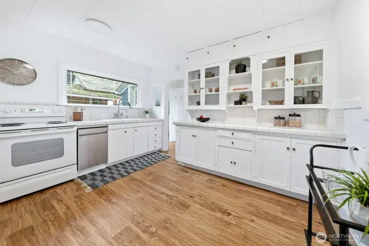 Recently refreshed with a new dishwasher, cabinetry, and paint. The kitchen beautifully balances old and new — showcasing timeless touches like open glass cabinets, classic tilework, and a vintage-style lazy Susan.