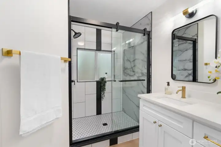 Frameless glass, matte black finishes, and marble-inspired tile create a spa moment worth lingering in.