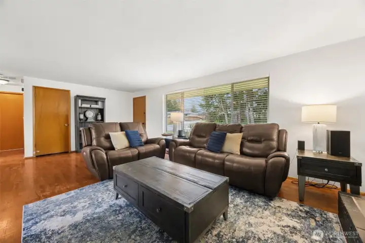 Bright open living area makes this room feel welcoming- large window & hardwood flooring.
