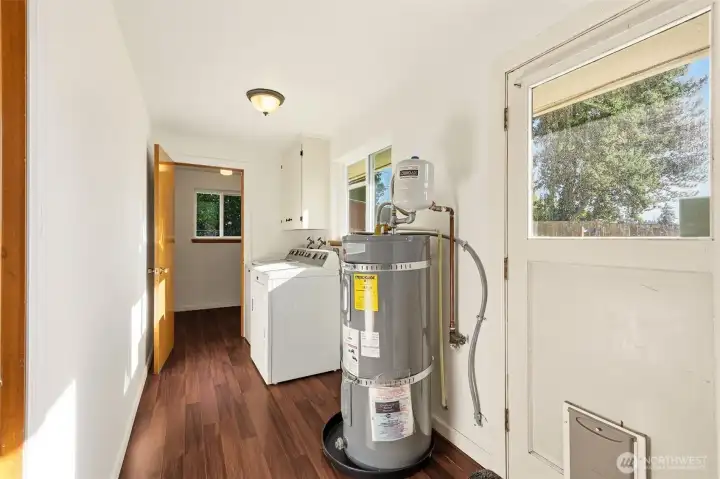 Laundry room with access door to backyard, newer hot water heater and leads to pantry for all your extra kitchen storage!