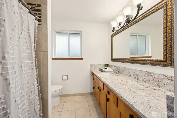 The updated bathroom includes a tile-surround tub/shower combo, granite countertops, and modern lighting. Lots of countertop room!