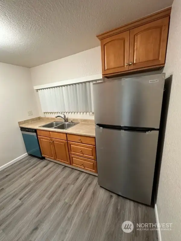 Stainless appliances in the kitchen with laminate flooring.