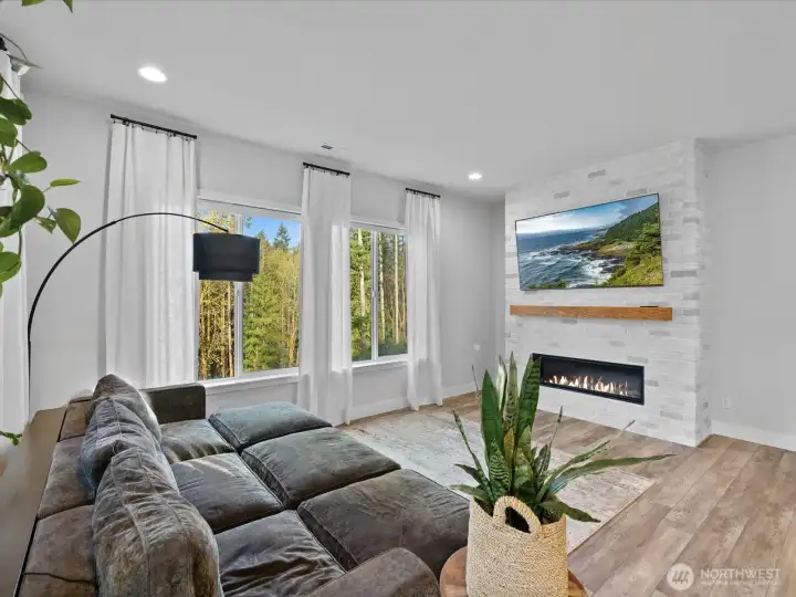 The main level living room features a fireplace and views of the forest behind the home.