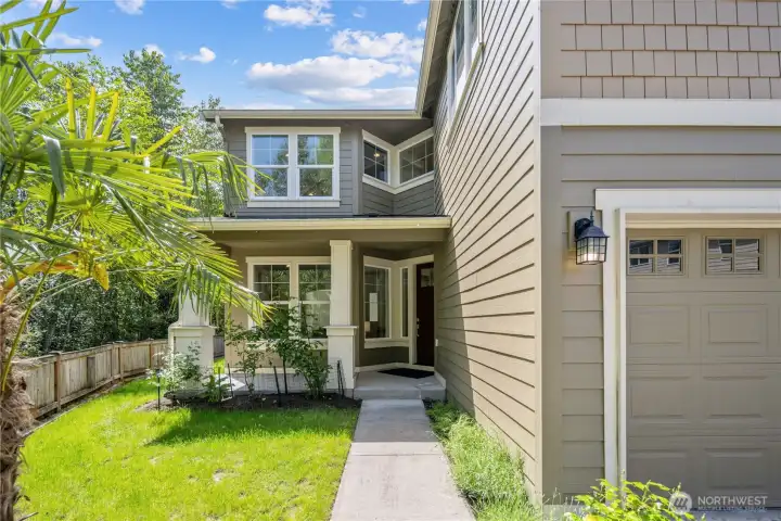 Tucked between the attached garage and lush greenbelt, the front yard feels private and inviting from the moment you arrive. A mature windmill palm adds a cheerful Northwest surprise, while Craftsman-style columns frame the large sheltered front porch with just one easy step to the front door.