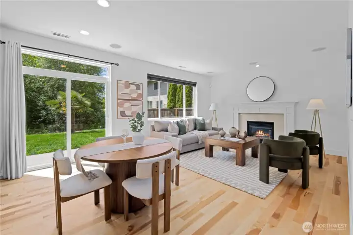 The family room carries the same graceful rhythm as the formal living room, with a gas fireplace centered at the far end to gather the space and make it feel warmly anchored. Recessed lighting brightens the room from above, adding an uplifting glow that keeps the whole area open and welcoming.