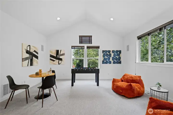 The vaulted bonus room opens up with tall ceilings, recessed lighting, and windows that pull in leafy views from multiple sides. It’s an easy space to imagine as a game room, media room, creative studio, homework zone, or relaxed hangout, with plenty of room to spread out while still feeling bright and lifted.