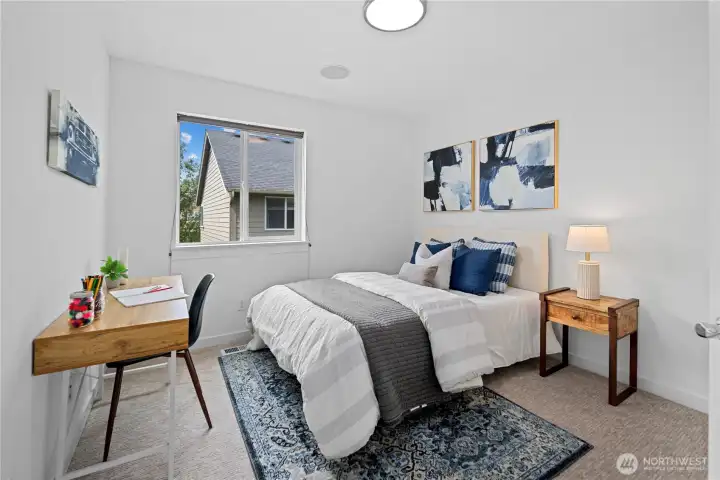 The three upstairs guest bedrooms sit in a small cluster, with this first bedroom on the right offering generous space, new carpet, a large closet, and a large west-facing window for sunset glows with blinds for privacy. Fresh paint in the same bright, cohesive color used throughout the home keeps the room connected, while the newvround flush-mount ceiling light casts a softer, more natural glow. Plenty of outlets and the built-in whole-house speaker system add everyday comfort.