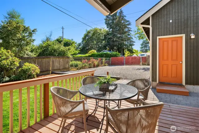 Looking off the back deck towards the huge parking area and detached garage. A double gate with red slats is at back property line.