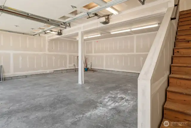 Looking across the garage there is a man door to the right at the bottom of the stairs.