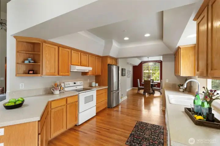 Large kitchen with oak floors leading to formal dining room.