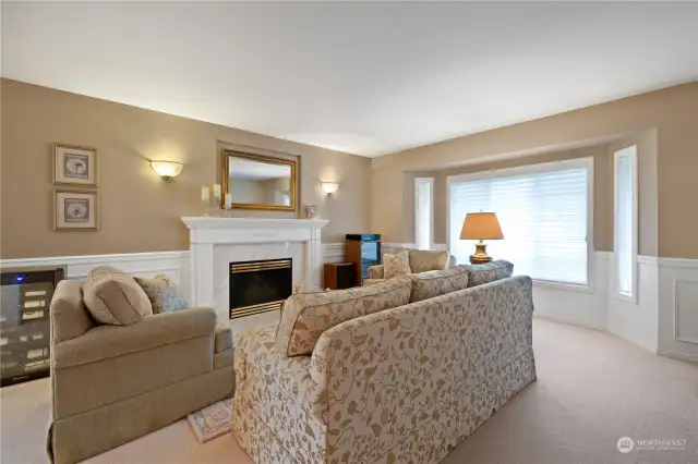 Formal but open living room with wainscoting and one of two gas fireplaces in the home.