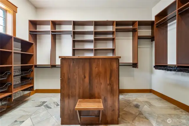 A dream closet for anyone who values organization and style. Custom built-in shelving and drawers line the walls, offering ample storage for clothing, shoes, and accessories.