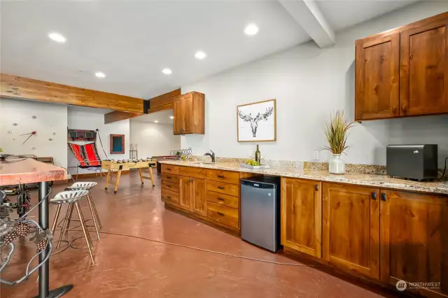 A well-appointed wet bar with stylish countertops, sink, and mini-fridge invites guests to mingle over drinks and a tempting array of snacks.