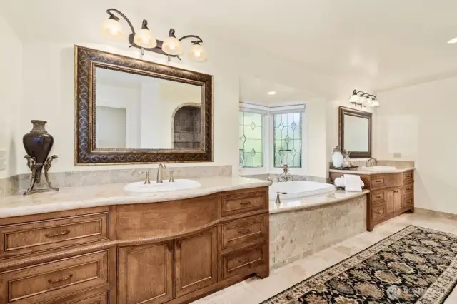 A 5-piece on suite spa inspired bath that includes over-sized shower, impressive soaking tub, custom cabinets, built in dresser, heated floors, and elegant stained-glass windows.