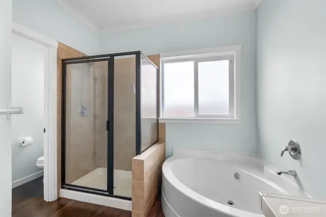 Glass wraps the tiled walk-in shower. Separate soaking tub.