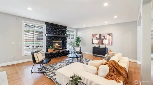 This inviting main living room centers around a striking black stone fireplace, creating a cozy statement feature that contrasts beautifully with the natural light and soft-toned finishes—ready to be styled with your personal touch